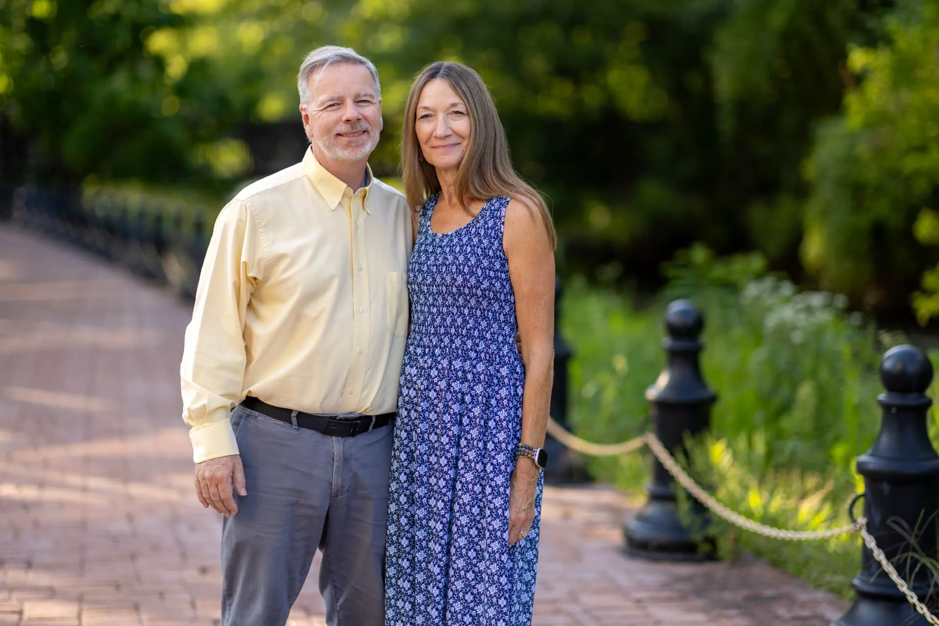 Cliff and Sue, founders of Masterpiece Journey, standing together on a garden bridge
